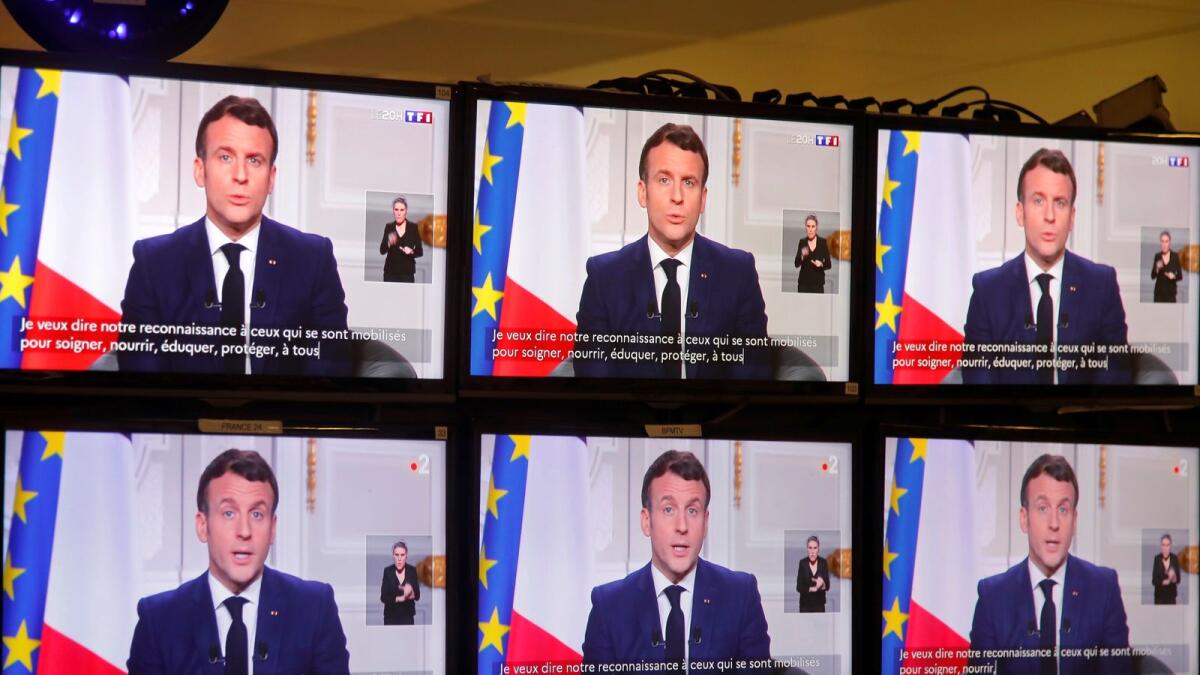 French President Emmanuel Macron is seen on screens as he delivers his New Year's speech to the nation at the Elysee Palace in Paris, France, December 31, 2020.