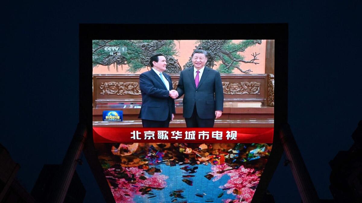 A large screen shows news coverage of Chinese President Xi Jinping (R) meeting former Taiwan president Ma Ying-jeou in Beijing on Wednesday. — AFP