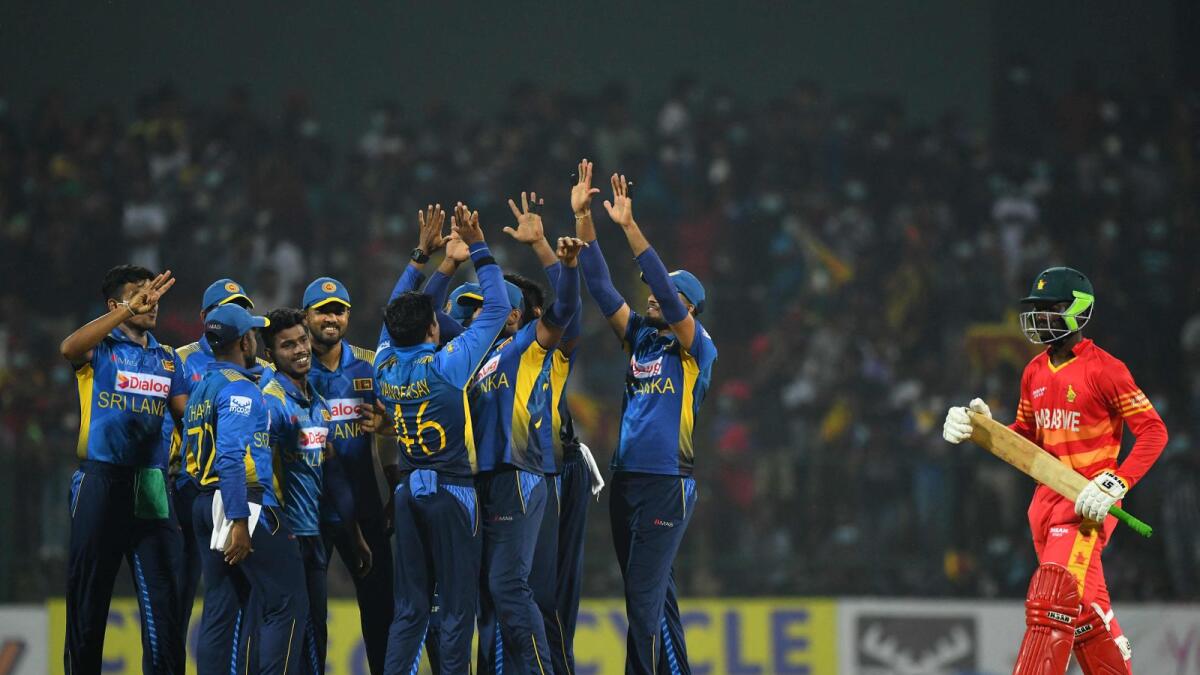Sri Lanka's Jeffrey Vandersay (centre) celebrates with teammates after taking the wicket of Zimbabwe's Takudzwanashe Kaitano (right). (AFP)