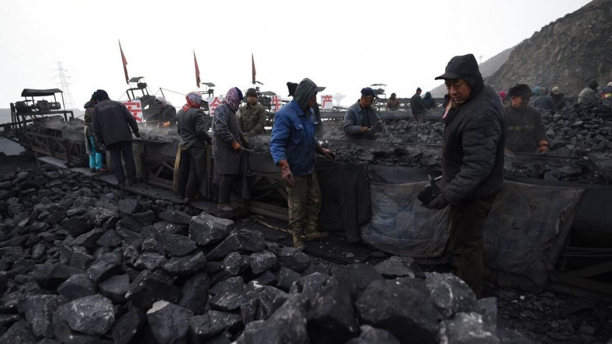 Workers sort coal on a conveyer belt near a coal mine in Datong, in China's northern Shanxi province.