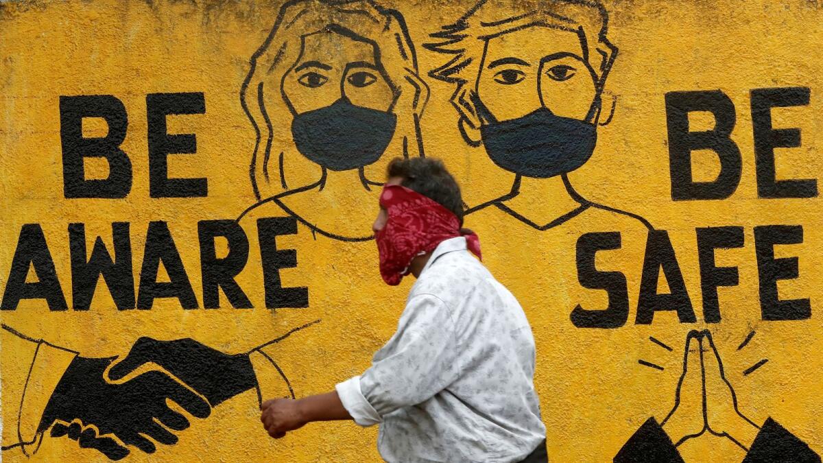 A man walks past a graffiti amid the spread of the coronavirus disease (COVID-19) in Mumbai, India, November 2, 2020.