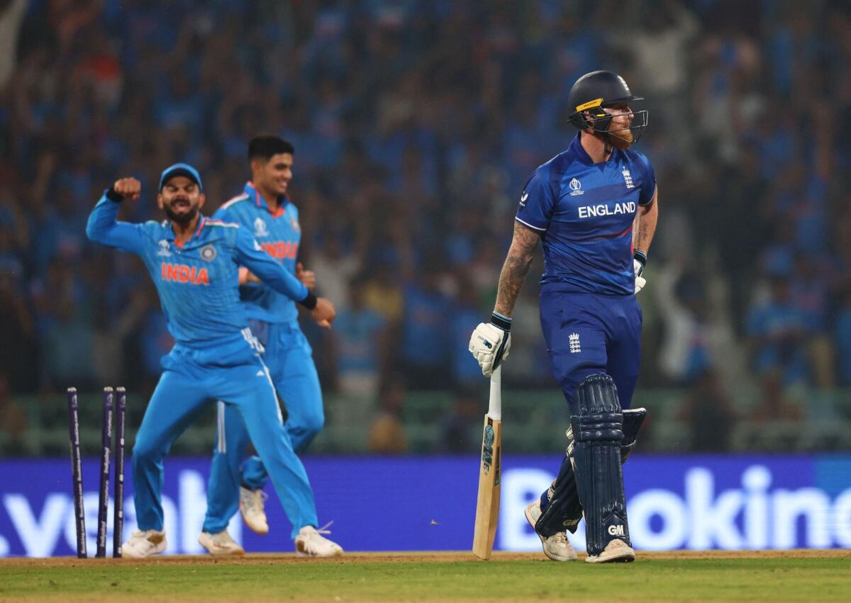 England's Ben Stokes walks off the pitch after losing his wicket as India's Virat Kohli celebrates. —  Reuters
