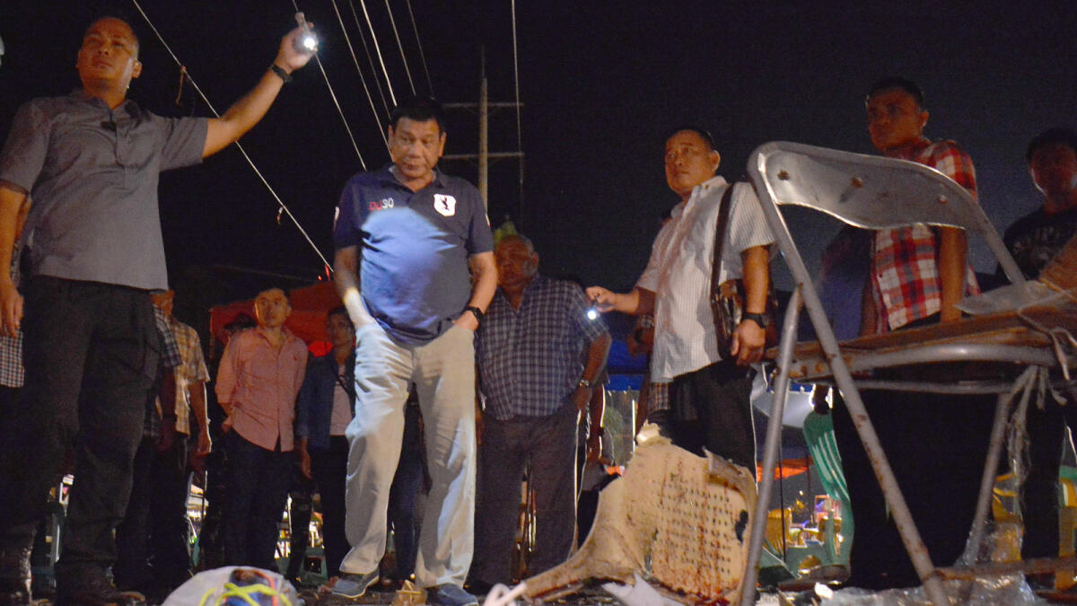 In this photo released by Malacanang Palace Presidential Communications Operations Office Presidential Photographers Division, Philippine President Rodrigo Duterte, second left, visits the site of Friday night's explosion that killed more than a dozen people and wounded several others at a night market in Davao city, his hometown, Saturday, Sept. 3, 2016 in southern Philippines. Duterte declared a nationwide 'state of lawlessness' Saturday after suspected Abu Sayyaf extremists detonated a bomb at the market. (Robinson Ninal/Malacanang Palace Presidential Communications Operations Office Presidential Photographers Division via AP)