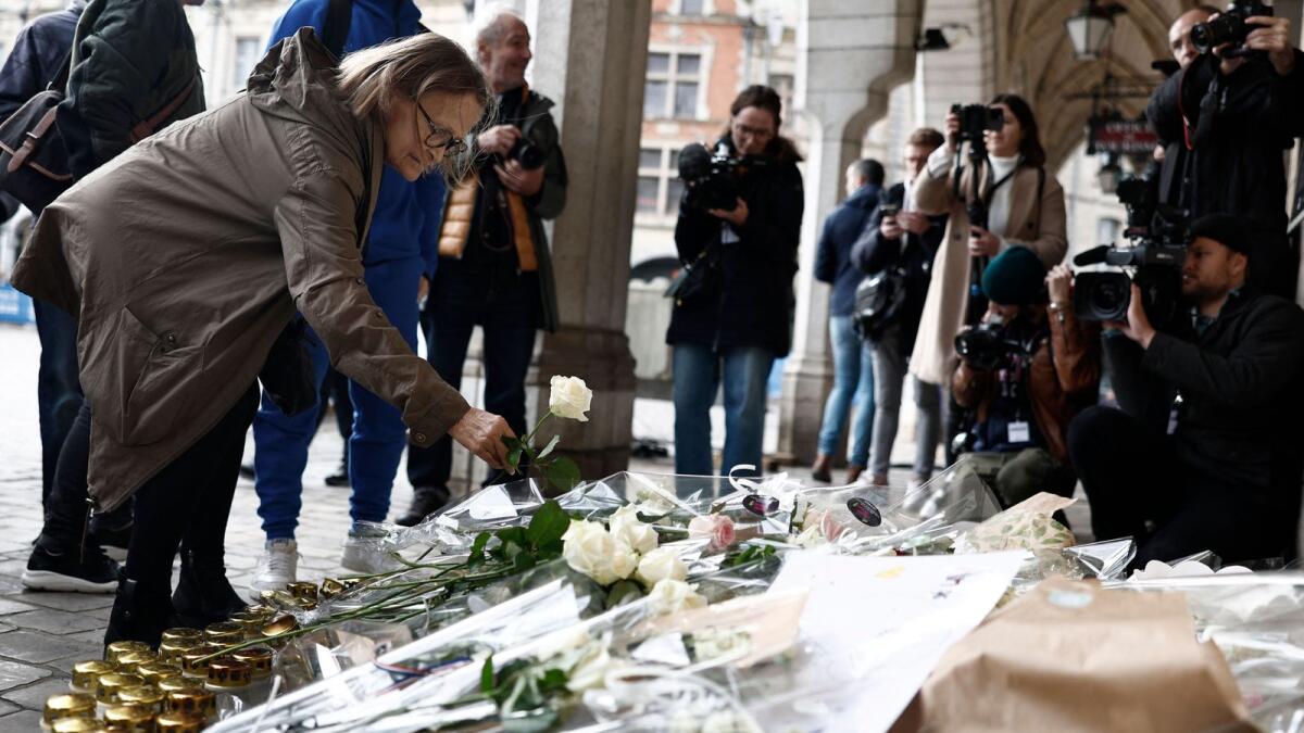 A local resident lays a flower as she attends the funeral ceremony for French school teacher Dominique Bernard at the town hall in Arras on Thursday. — AFP