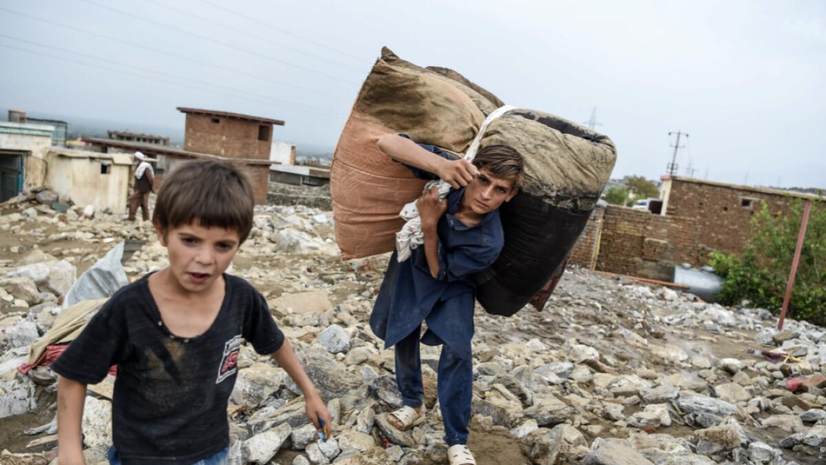 A young villager retrieves belongings from the debris of houses after a flash flood affected the area at Sayrah-e-Hopiyan in Charikar, Parwan province. The death toll from flash floods that swept through an Afghan city climbed to 100 on August 26, officials said, as rescue workers searched for survivors in the rubble of collapsed houses. Photo: AFP