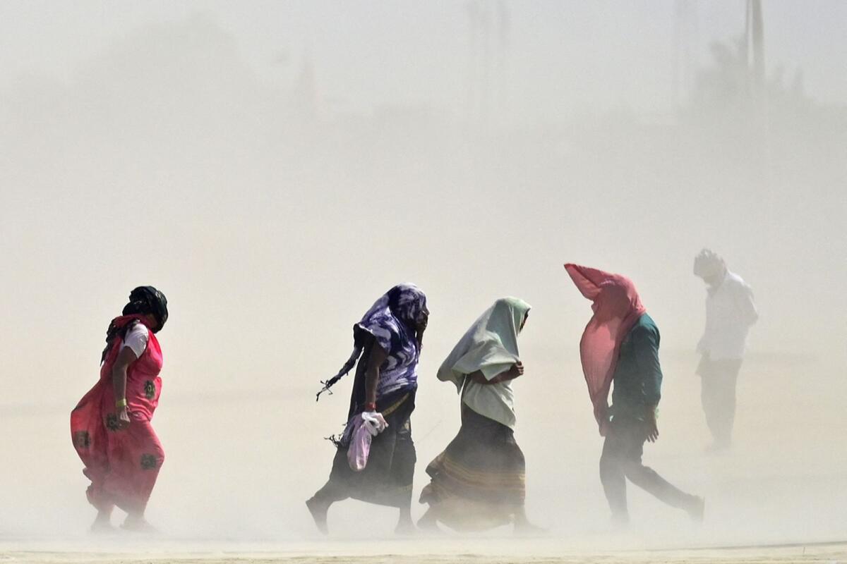 People walk through a dust storm on a hot summer day in Prayagraj, India, on April 18, 2023. — AFP