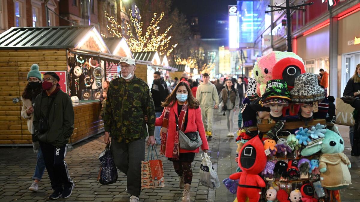 Shoppers, some wearing face coverings to combat the spread of Covid-19, walk past stores on the Monday before Christmas in Manchester in north-west England on December 20, 2021. Photo: AFP