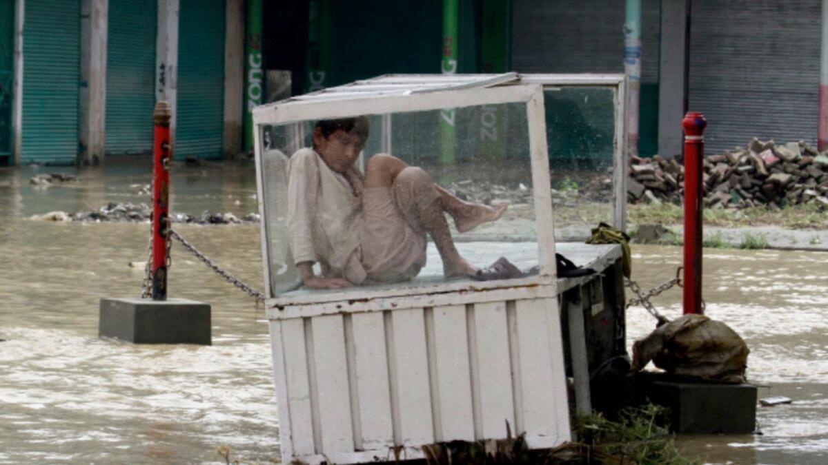 A Pakistani boy site under his stall in a flooded area on the outskirts of Peshawar. — AP