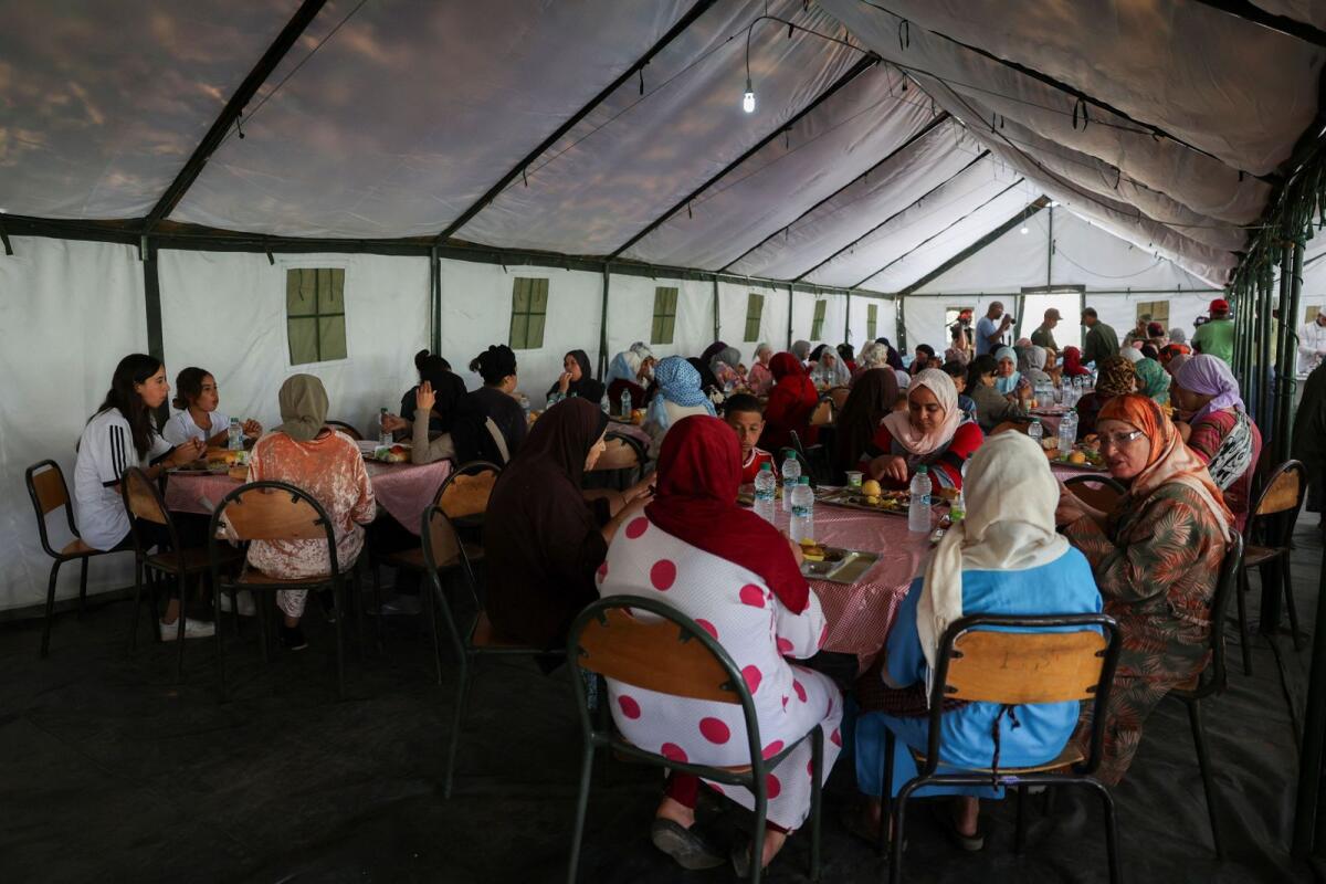 Women and children sit and eat a meal in a military aid camp where they reside following the deadly earthquake in Amizmiz, Morocco, on Sunday. — Reuters