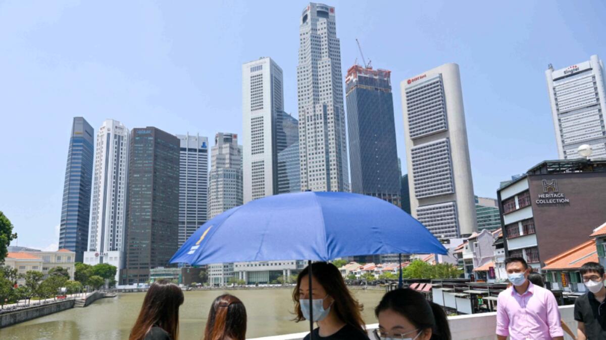 People walk along a bridge next to the financial business district in Singapore on April 20. — AFP
