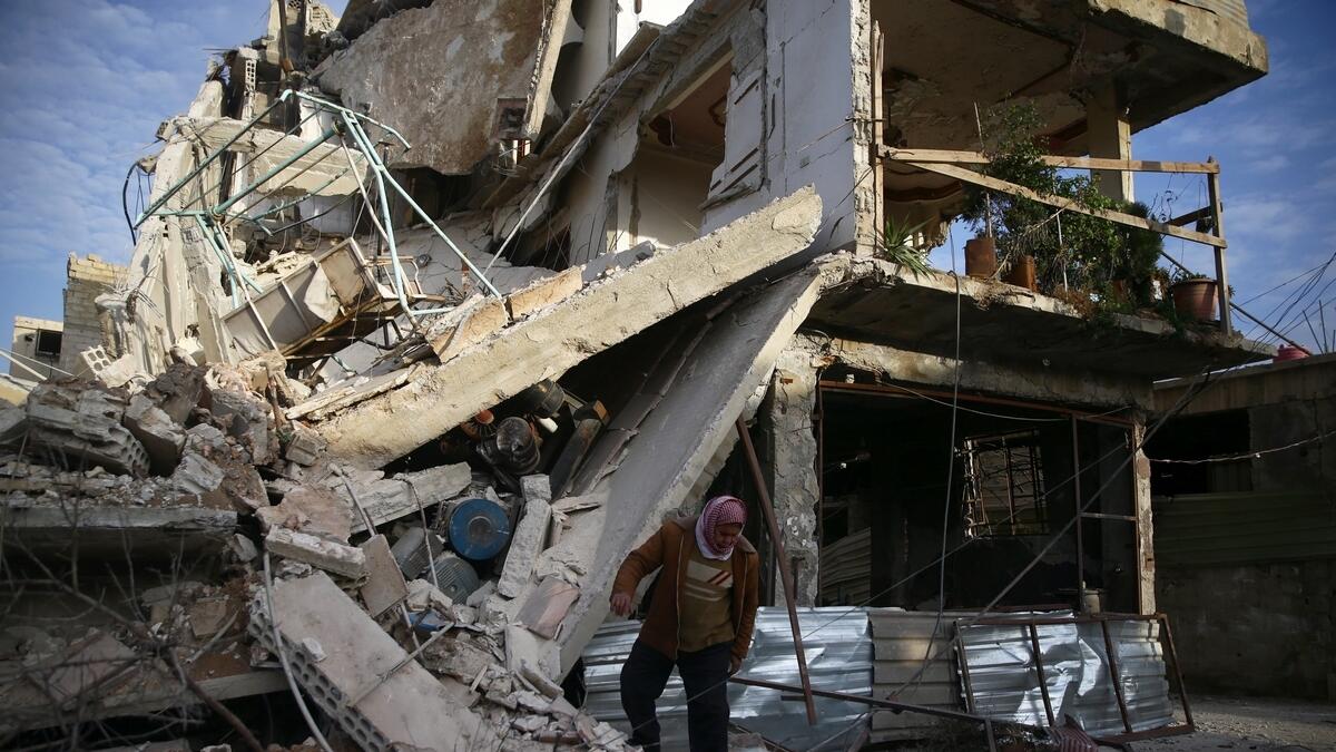 A person inspects damaged building in the besieged town of Douma, Eastern Ghouta, Damascus, Syria.-Reuters