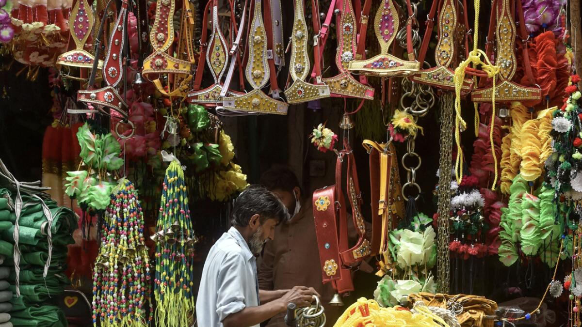 A vendor waits for customers at his shop selling items used to decorate animals for the upcoming Eid Al Adha festival  in Lahore, Pakistan. Photo: AFP