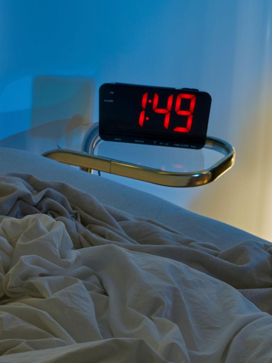 A bedroom clock next to an unmade bed, in Los Angeles, on Dec. 19, 2022. (Joyce Lee/The New York Times)