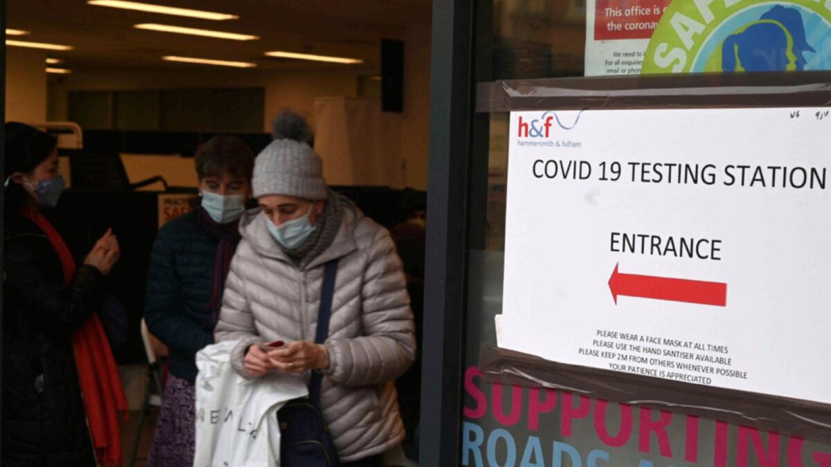 A woman walks past Covid-19 signage displayed at a centre in Hammersmith and Fulham in Greater London. — AFP