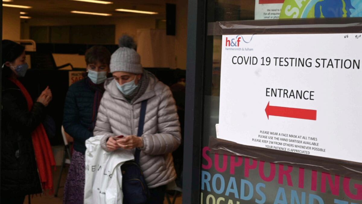 A woman walks past Covid-19 signage displayed at a centre in Hammersmith and Fulham in Greater London. — AFP