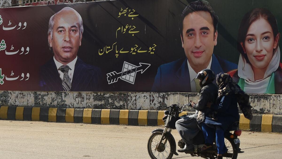 Commuters ride past an election campaign poster of the Pakistan Peoples Party (PPP) in Karachi on Wednesday. Photo: AFP
