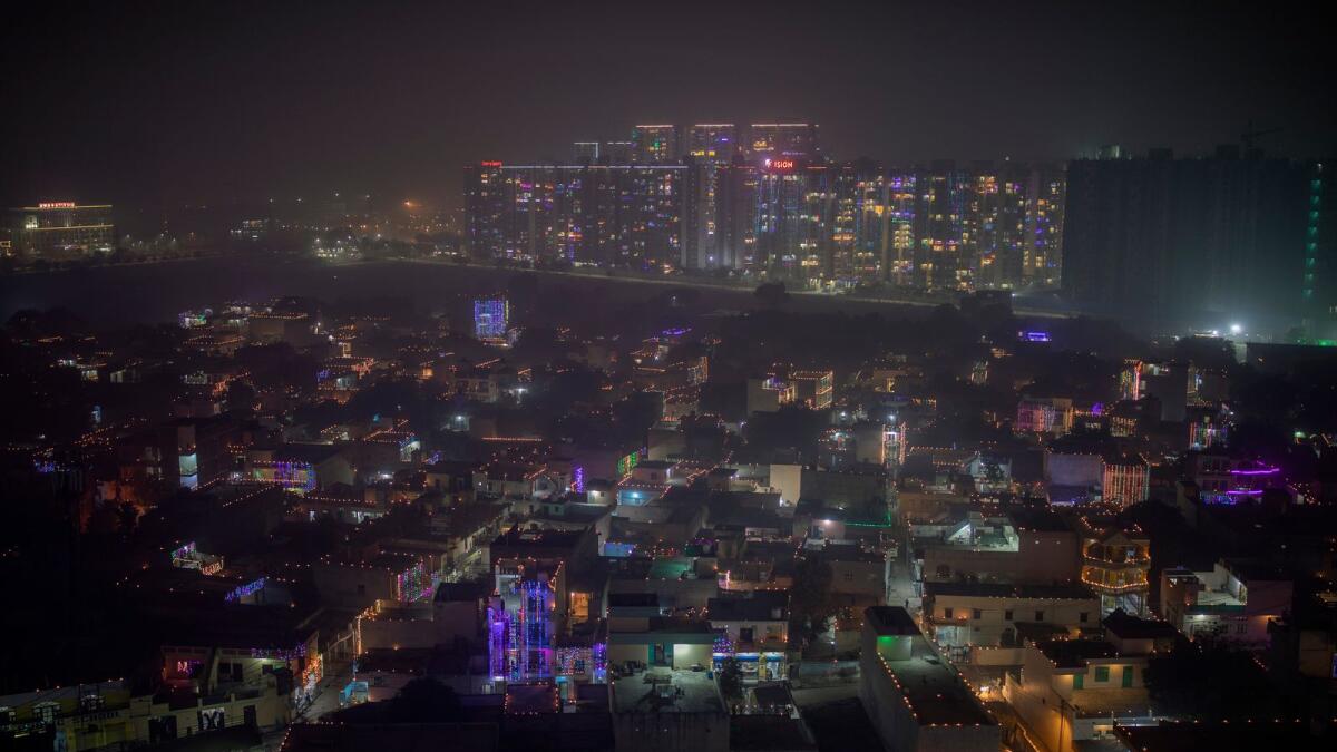 A layer of smog envelops the skyline as residential buildings are decorated with colorful lights during Diwali on the outskirts of New Delhi, India. AP