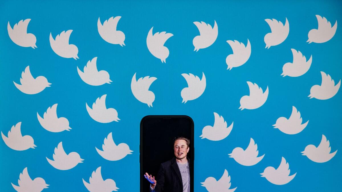An illustration photo shows a cellphone displaying a photo of Elon Musk placed on a computer monitor filled with Twitter logos in Washington, DC. — AFP file