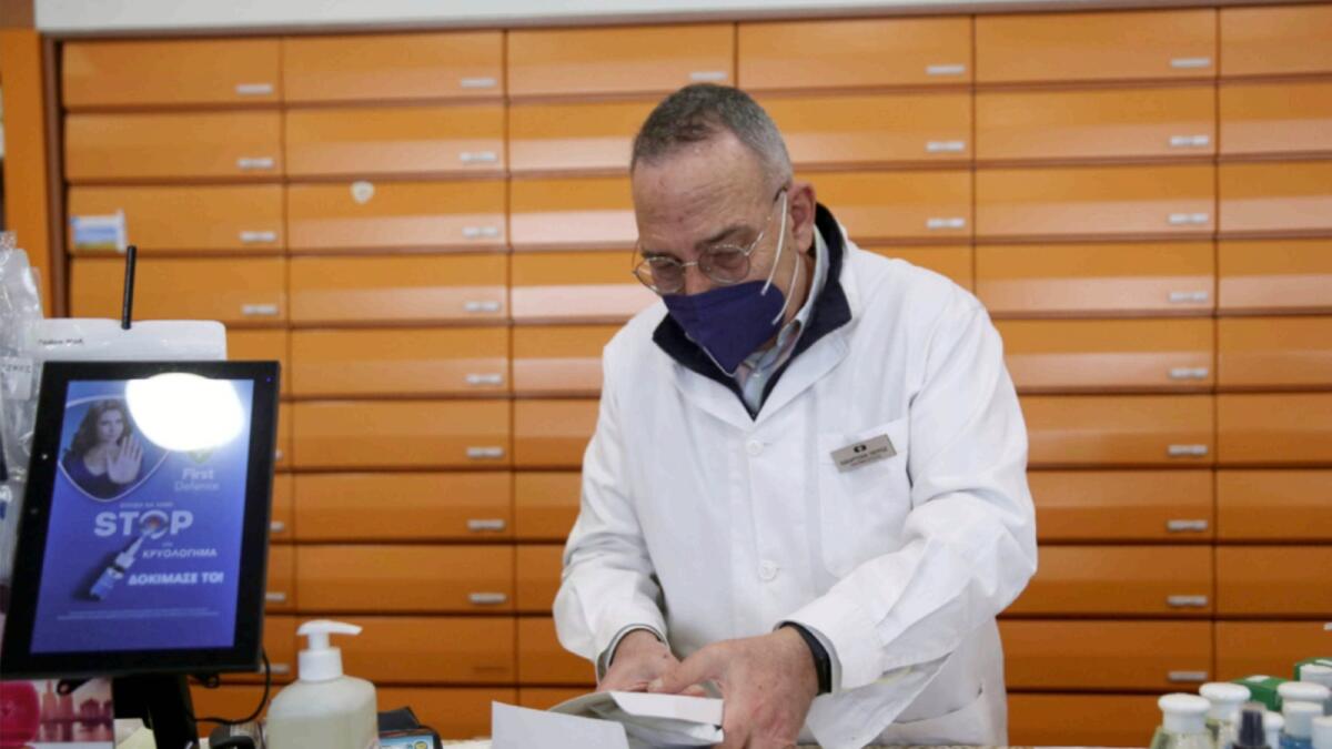 A pharmacist holds a box with rapid antigen Covid-19 self-testing kits at his drugstore, as the country starts free distribution in Athens. — Reuters