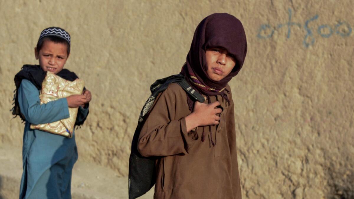 Afghan children walk along a street to go to their school in Kandahar. — AFP