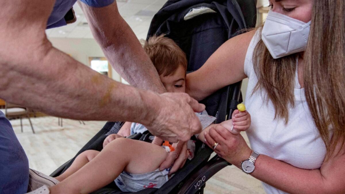 A mother holds her one and a half year old son as he receives the child Covid-19 vaccine in his thigh at Temple Beth Shalom in Needham, Massachusetts. — AFP