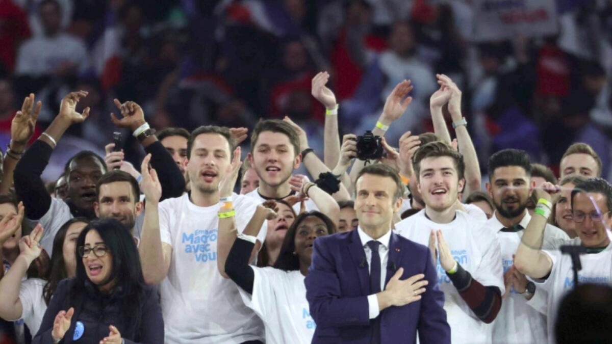 French President Emmanuel Macron, surrounded by supporters, gestures at the end of his first campaign meeting at the Paris La Defense Arena. — AFP