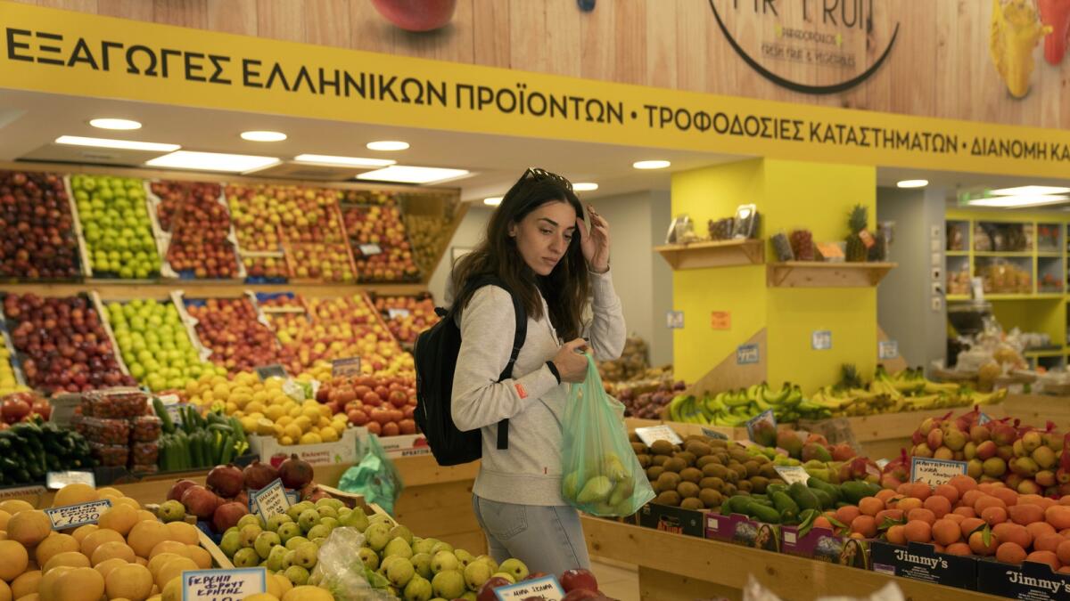 A woman shops at a grocery store in Athens, Greece. The small shift in numbers doesn’t change what households already are experiencing: rising prices at the grocery store. — AP