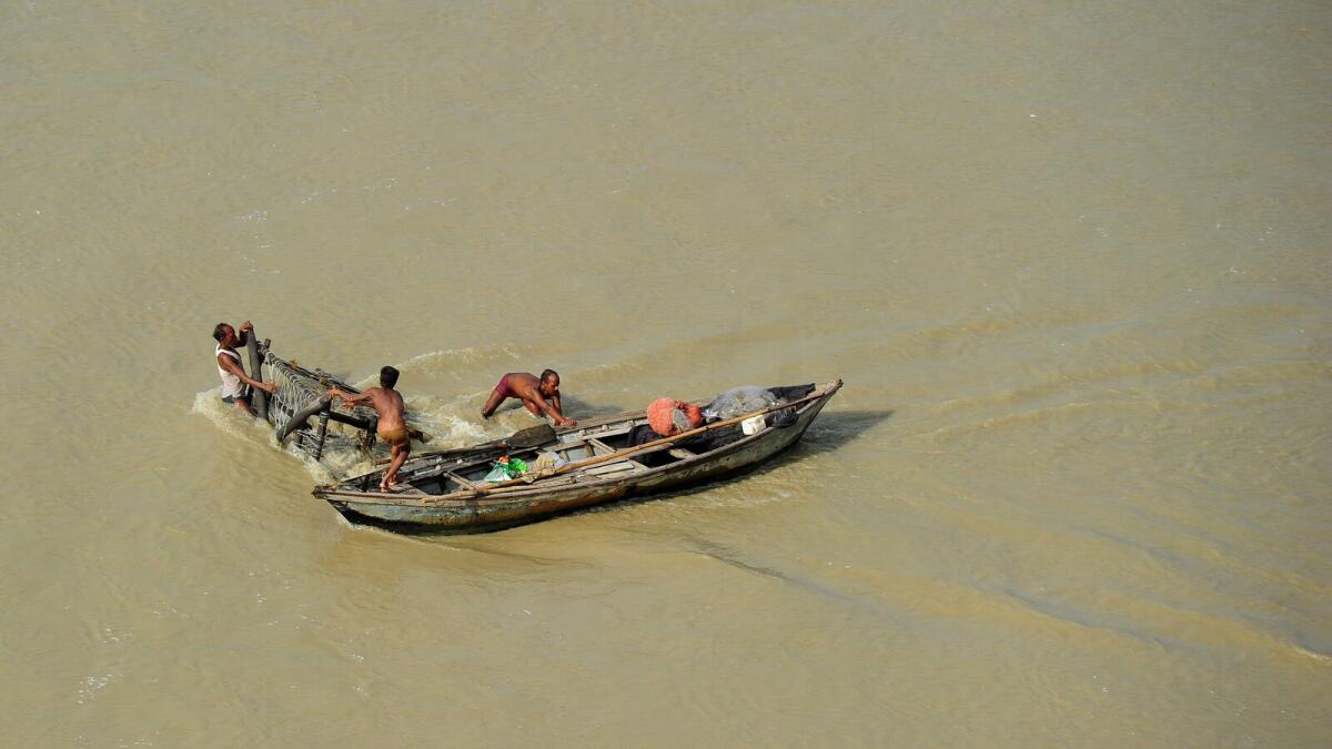 A boatman tries to anchor his boat in the middle of the flooded river Ganges to catch fish in Allahabad in Uttar Pradesh. —  AFP