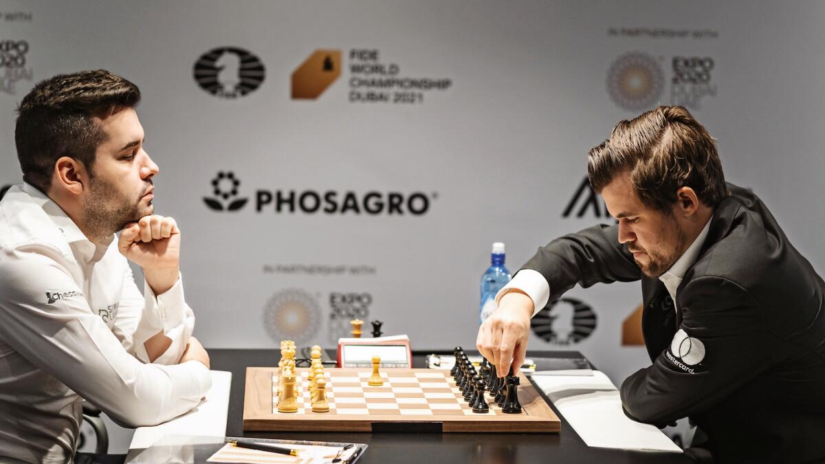 Intense battle: Magnus Carlsen makes his move as Ian Nepomniachtchi looks on in the World Chess Championship match on Tuesday. — FIDE