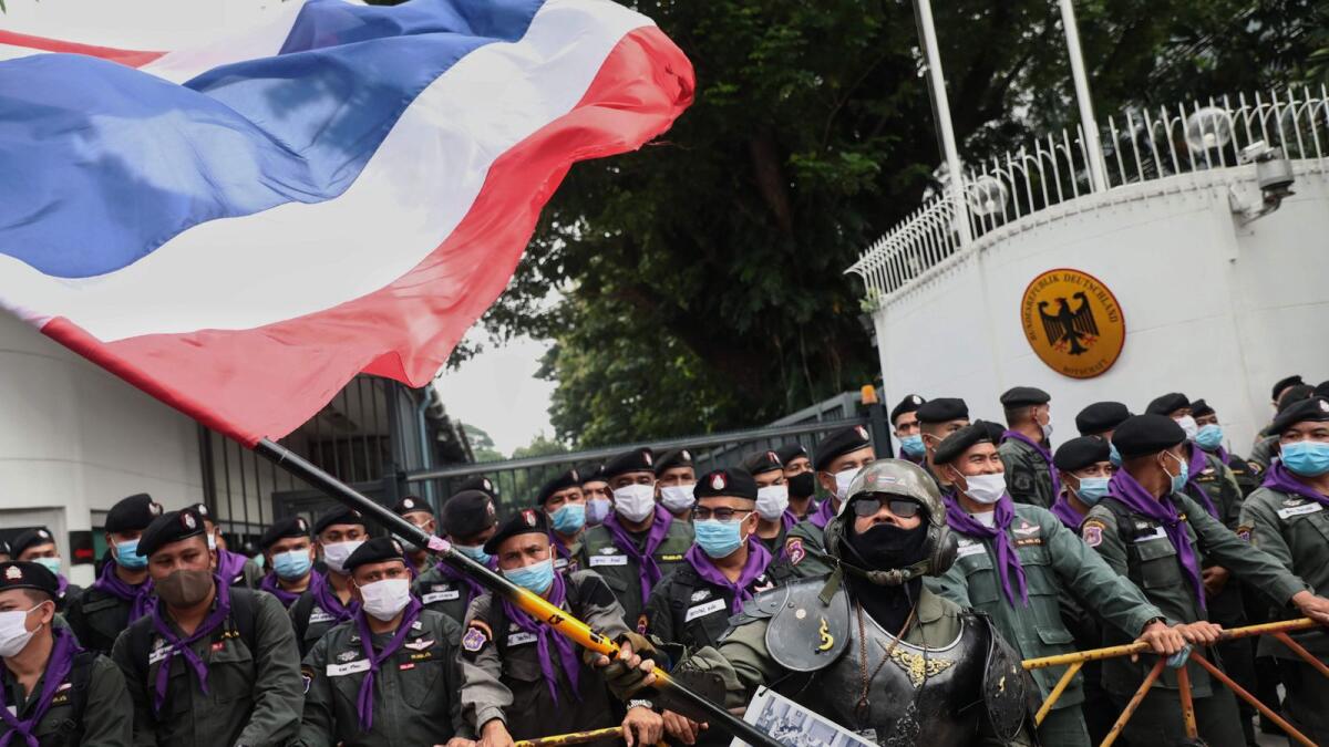A royalist supporter waves a large Thai national flag in front of police standing guard during a rally outside the German embassy to show support for the Thai royal establishment in Bangkok on Monday.