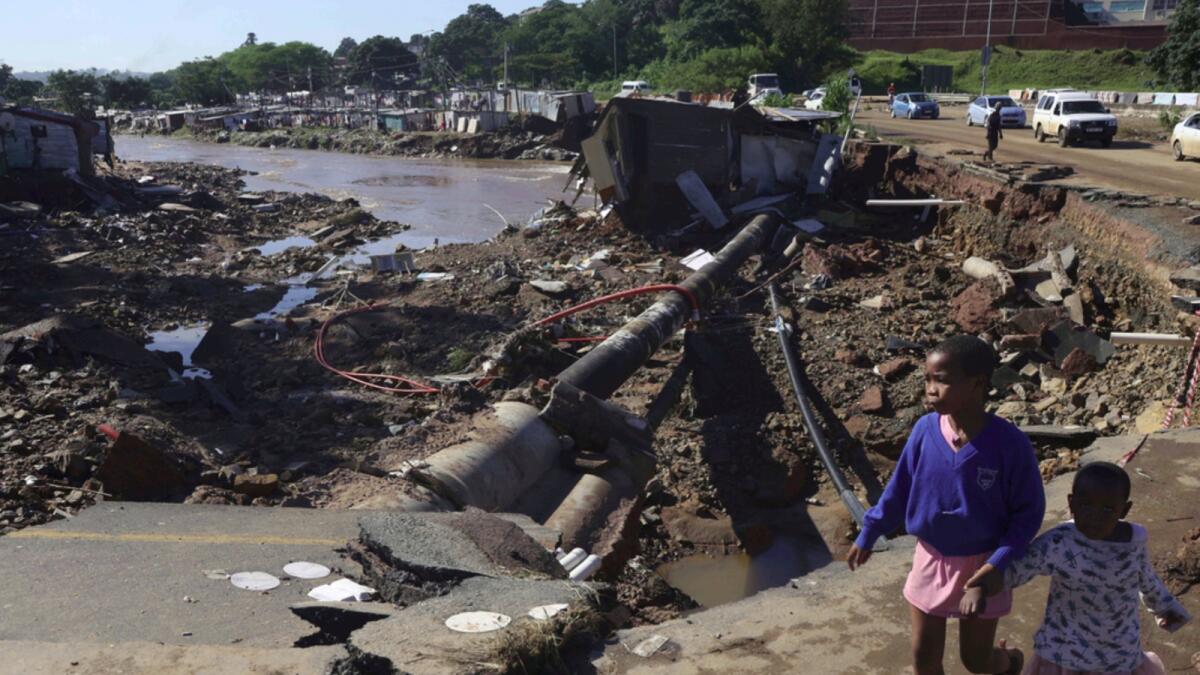 Children walk on damaged road at an informal settlement in Durban. — AP