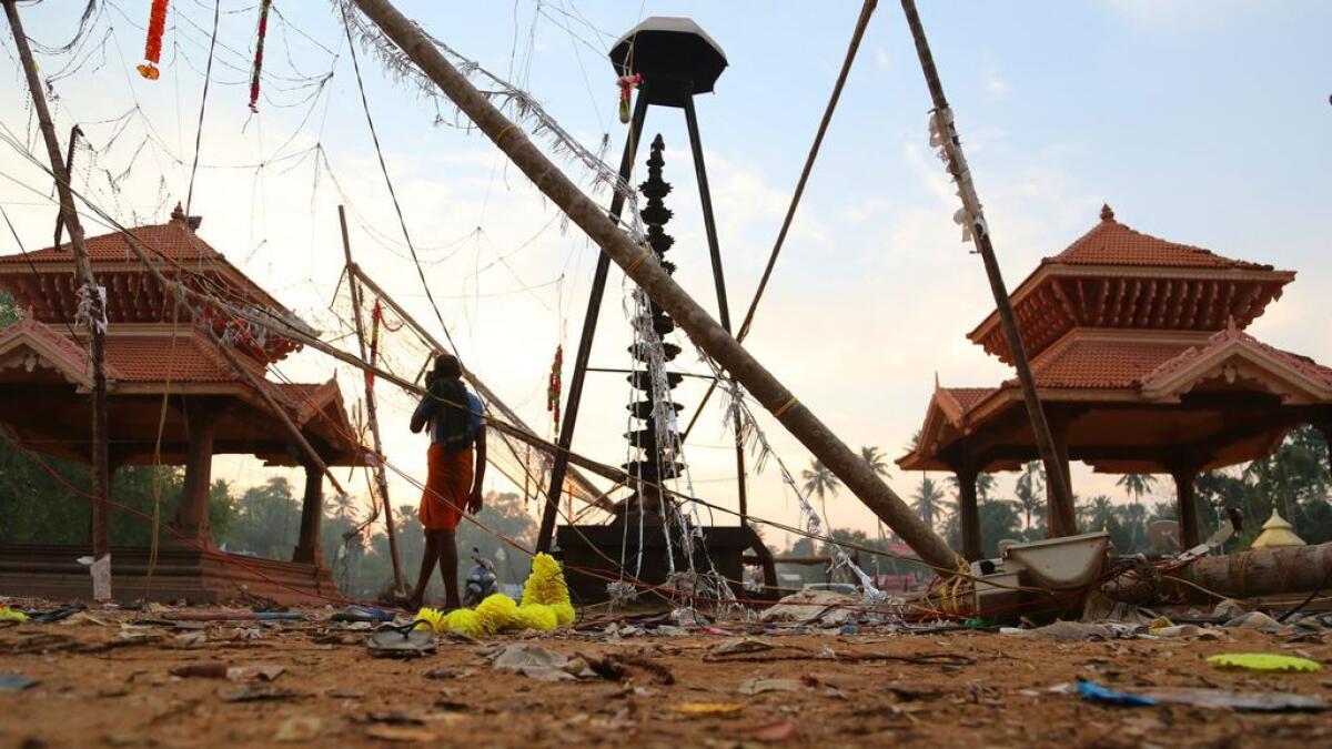 A man walks past damaged structures at the spot where a massive fire broke out during a fireworks display at the Puttingal temple complex in Paravoor village, Kollam district. 