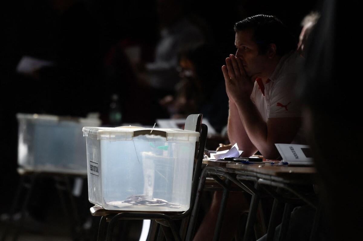 An election staffer gestures while waiting for voters during the referendum for Chile's new constitution proposal, in Santiago, on December 17, 2023. — AFP file