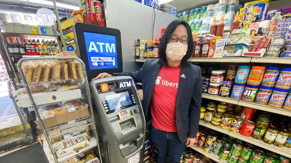 LibertyX CEO Chris Yim poses next to his company's ATM for Bitcoin transactions installed at 'Market Deli' in New York City. — Reuters