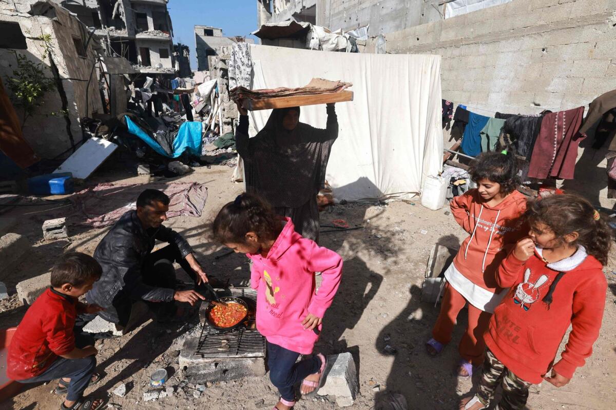 A man prepares food on a street next to destroyed houses in Rafah on the southern Gaza Strip on December 11, 2023. Photo: AFP
