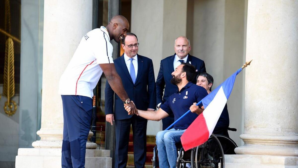 French gold medal winner and judoka Teddy Riner (L) flanked by French President Francois Hollande (2nd L) shakes hands with Frances flag bearer Michael Jeremiasz for the Rio Paralympic Games 