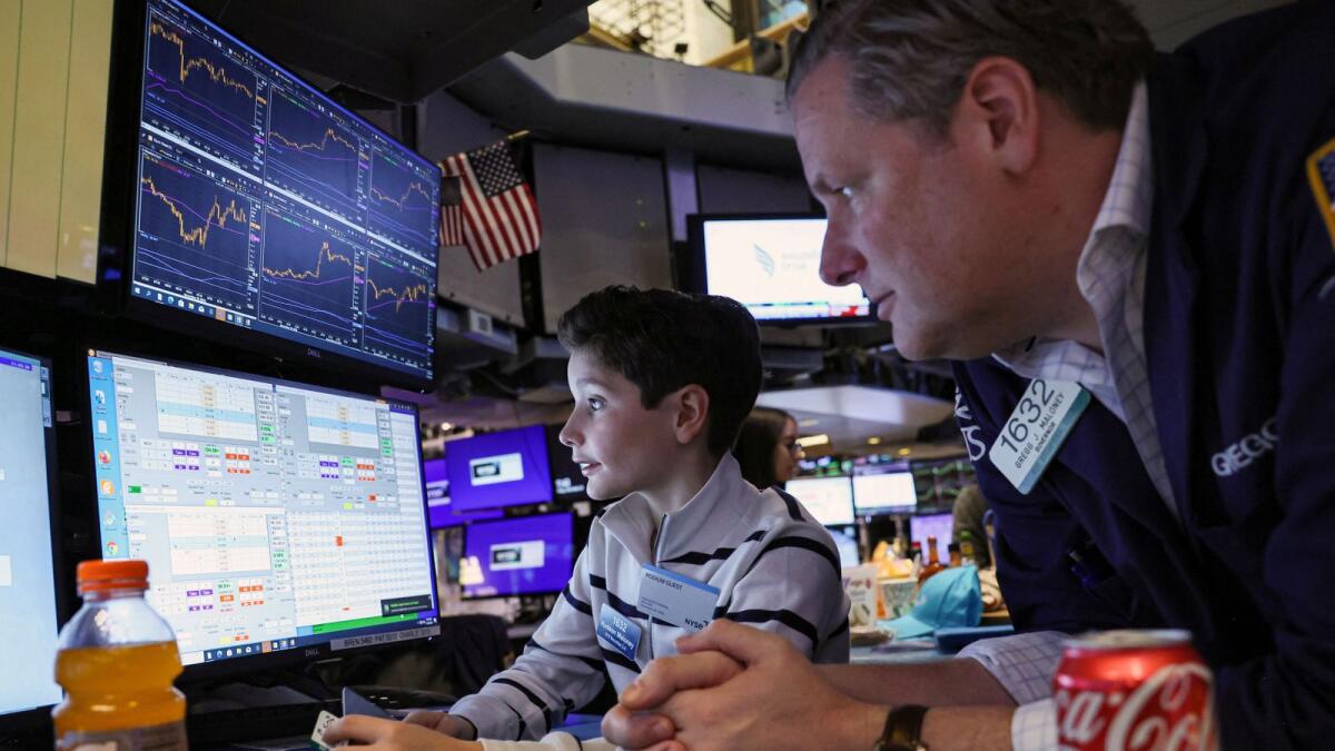 A trader works with his son during a traditional bring-your-kids-to-work day on the floor at the New York Stock Exchange on Friday. — Reuters