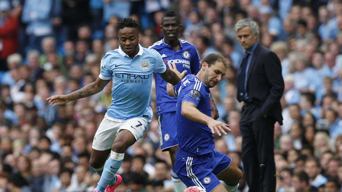 Chelsea manager watches as Manchester City’s Raheem Sterling vies for the ball with Chelsea’s Branislav Ivanovic during their English Premier League match.