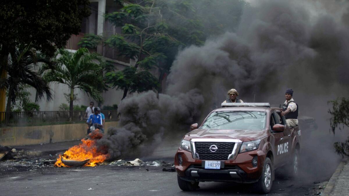 Police drive their car over a barricade set up by taxi drivers to protest fuel shortages in Port-au-Prince, Haiti. — AP