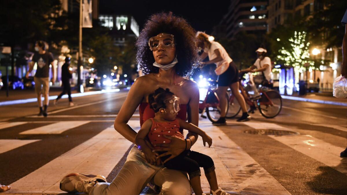 Demonstrator Twana Buck and her daughter Bonita sit in the street near the White House as protests triggered by the death of George Floyd while in police custody, continue in Washington, DC. Photo: AFP