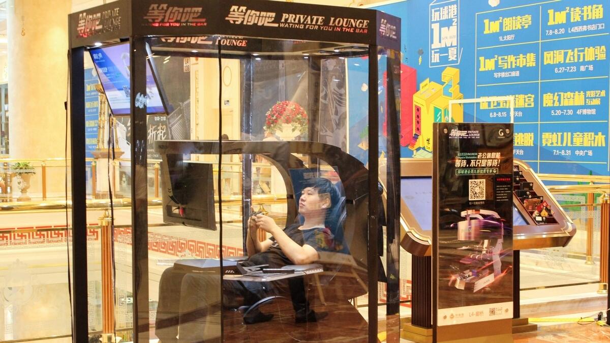 A man playing video games in a booth at a shopping mall in Shanghai.