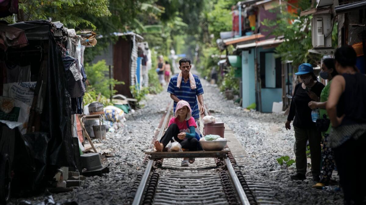 A vendor pushes an improvised cart with a woman and merchandise along a rarely used rail track in Bangkok, Thailand. Daily life in the capital slowly returns to normal as Thai government eases many restrictions imposed weeks ago to combat the spread of Covid-19. Photo: AP