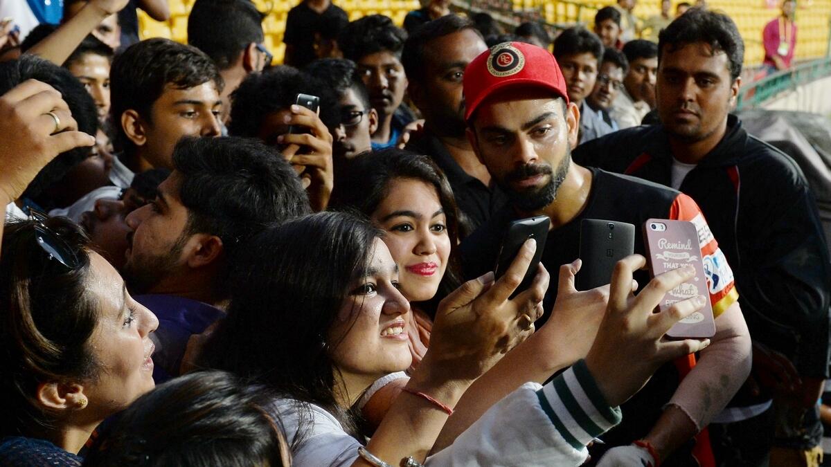 Fans take selfies with Virat Kohli after an IPL match in India. This year's IPL will be played behind closed doors due to the Covid-19. (AFP)