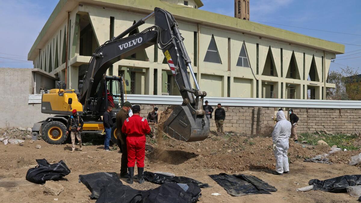 Iraqi forensic personnel examine human remains unearthed from a mass grave recently discovered in the northern Iraqi city of Mosul. — AFP