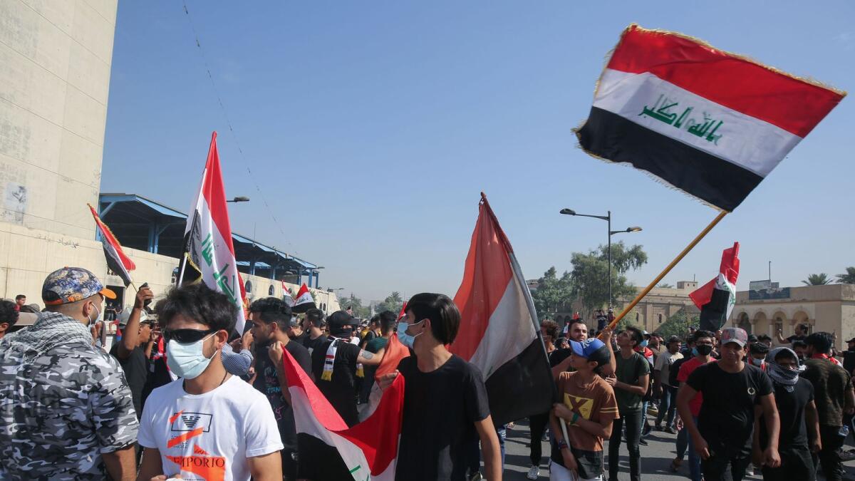 Iraqi demonstrators wave flags as they gather in Tahrir Square in the centre of the capital Baghdad on Sunday, to mark the first anniversary of a massive anti-government movement demanding the ouster of the entire ruling class accused of corruption.