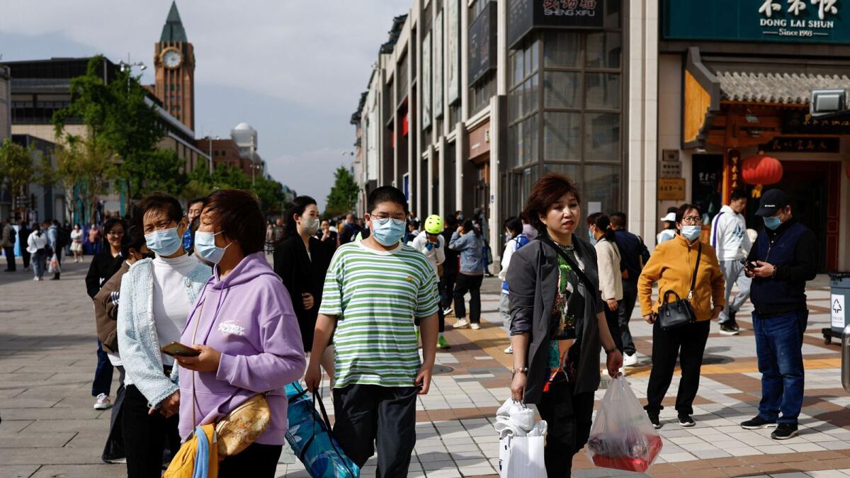 People walk at a shopping street in Beijing. - Reuters