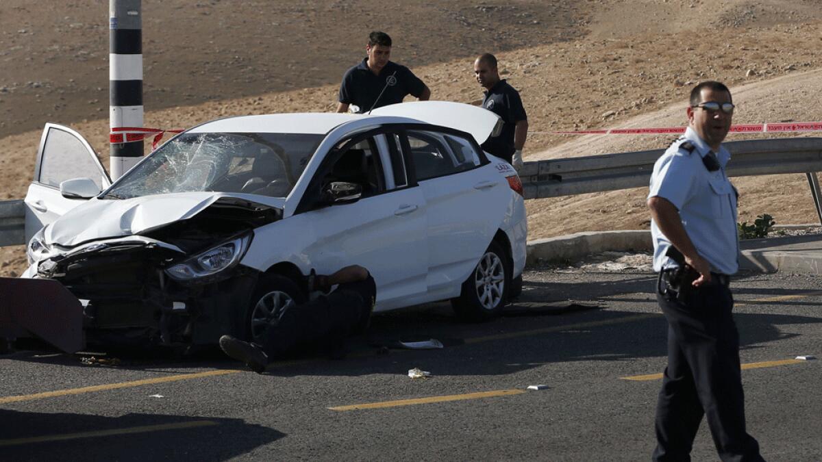Israeli security forces stand at the site where a Palestinian man rammed his car into Israelis soldiers standing by a bus station on a highway next the Jewish settlement of Kfar Adumim in the occupied West Bank.
