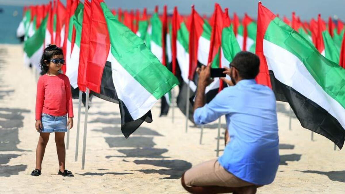 A father takes a photo of his daughter with the flags at the Kite Beach in Dubai. Photo by Dhes Handumon/ Khaleej Times