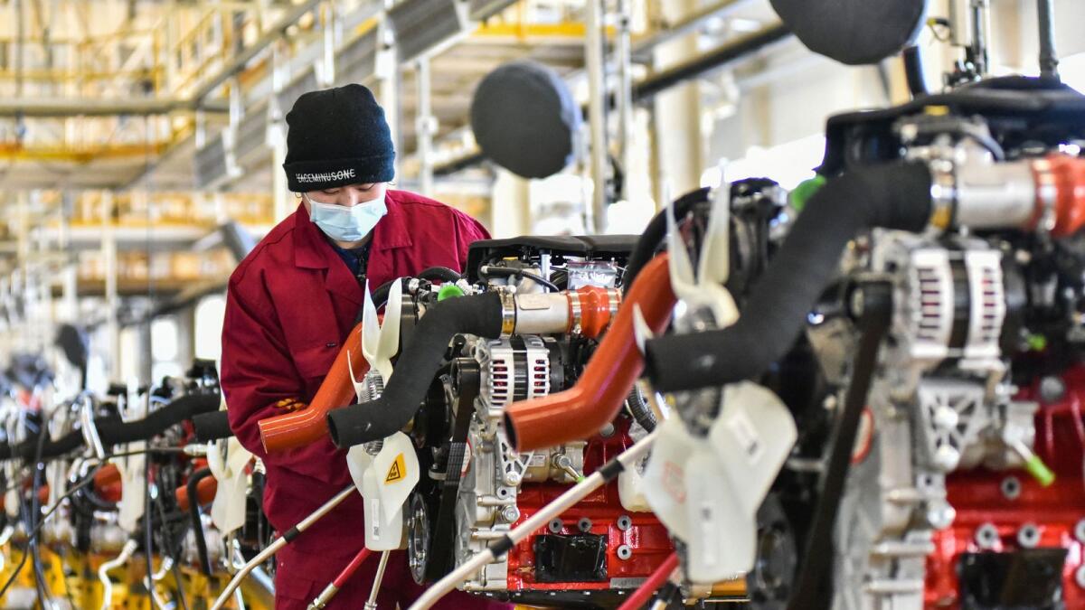 An employee works on a vehicle assembly line at an automotive factory in Qingzhou, China. - AFP