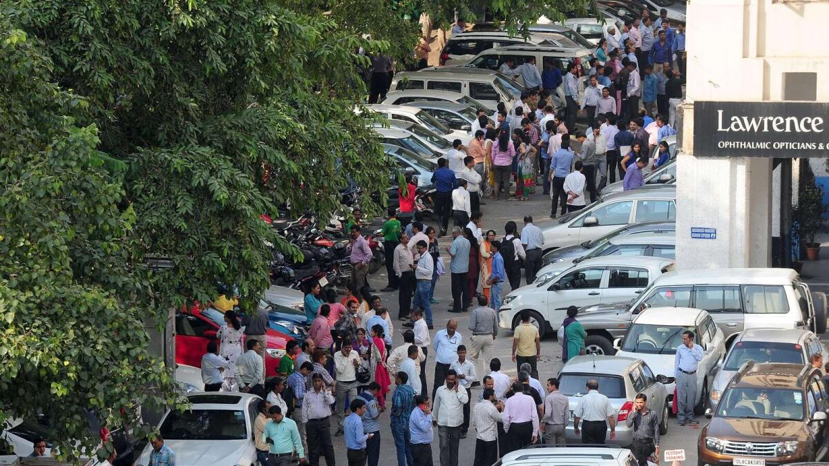 Indian office workers stand in an open area in a carpark following an earthquake in New Delhi on October 26, 2015.